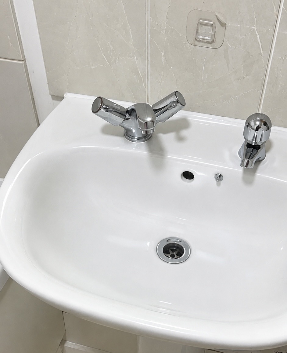 Bathroom basin, chrome taps and surrounding tiles — after cleaning